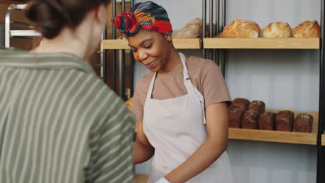 Schöne-Schwarze-Frau,-Die-Frisches-Brot-In-Der-Bäckerei-Verkauft